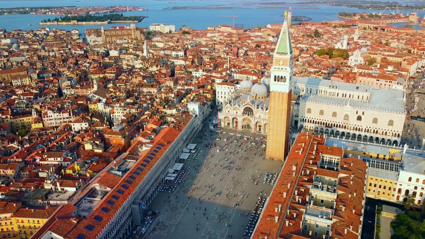 Aerial view of the city on the water and rooftops, the bell tower of the basilica and the unique canals with boats, crossing Venice and Italy. Gondolas with tourists. Carnival and Film Festival. Masks