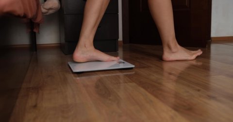 Woman putting in bed and weighing on floor scales closeup 4k movie
