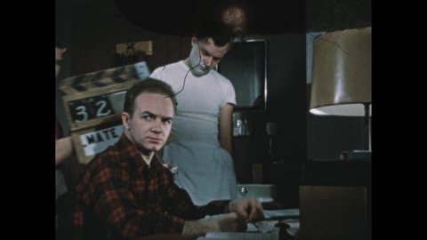 1950s: Boy sits at desk in college dorm room and speaks to friend at basin.