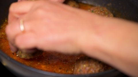 Cooking meatballs with tomato sauce in a pan 