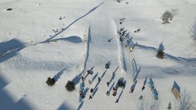 People (children and adults) ride in the winter on a hill on tubes and sleds. Sports winter sports, winter recreation. Construction aerial view height, drone video