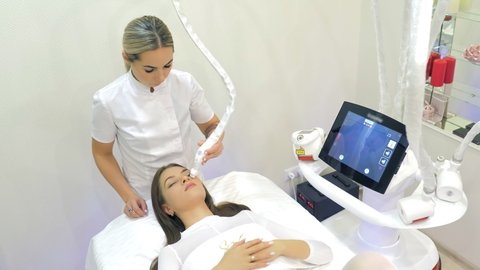 LPG skin massage in a professional beauty studio. A cosmetologist-therapist gives a rejuvenating facial massage to a beautiful client in a special white suit, in a beauty salon. Hardware massage