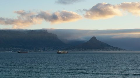 Famous Table Mountain Facing The Tranquil Waters In Capetown City, South Africa With Sailing Ships During Sunset. Static
