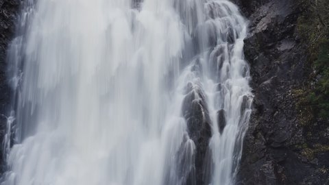 Storfossen waterfall in Norway. A powerful stream of water cascadines over blackened rocks. Slow-motion, long exposure.
