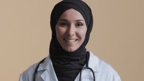 Young muslim professional woman female doctor physician in hijab white medical uniform consulting remote patient looking at camera webcam virtual video chat providing distant medical services teach