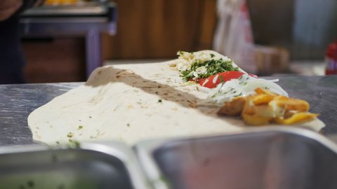 the cook cooked a kebab on a skewer and put it on a pita bread with vegetables, pulling a skewer out of a hot kebab. Fresh natural food in a national restaurant