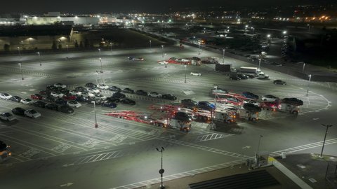 Tesla factory, Fremont. USA Nov. 2022. Vehicle loading at night with bright LED lighting above. Aerial footage of large parking lot for new energy efficient cars by the plant. High quality 4k footage
