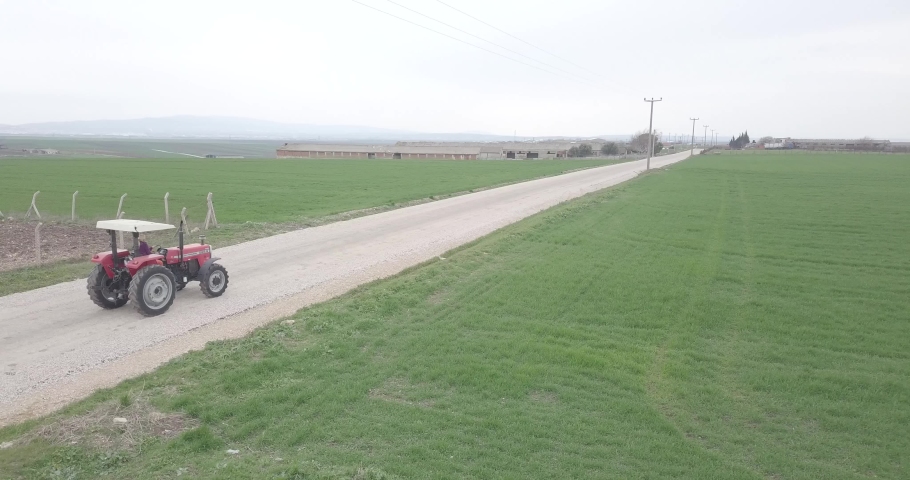 a tractor driving on the road between green fields