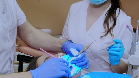 A dentist treats a woman's teeth using a cofferdam. Dental equipment.