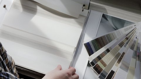 Woman fliping through catalog with roller blinds or window shade. Duo window roller system day and night. Choice of roller blinds.