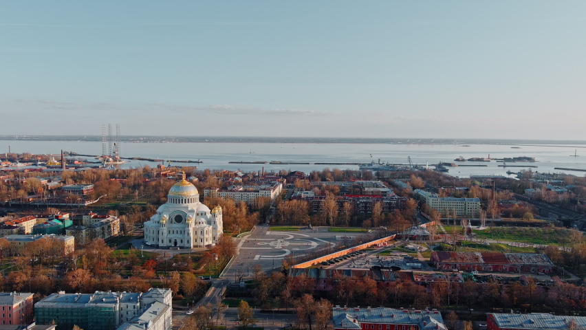 Aerial view of the sea capital of Russia Kronstadt at sunset, the golden dome of the huge main naval cathedral of St. Nicholas, the seaport with warships, dry docks, fortifications with cranes