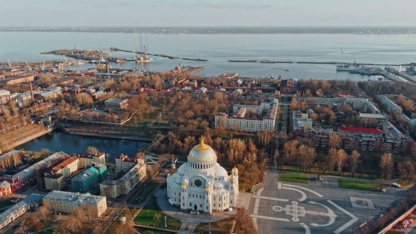 Aerial view of the sea capital of Russia Kronstadt at sunset, the golden dome of the huge main naval cathedral of St. Nicholas, the seaport with warships, dry docks, fortifications with cranes