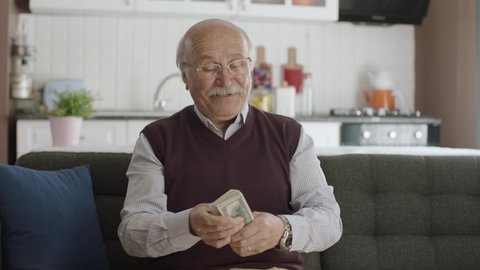 Happy old man very happy with his money. Winning the online lottery lottery. The old man is making a fan out of dollars.