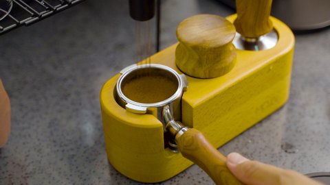 close up of a man distributing and tamping a ground coffee on portafilter