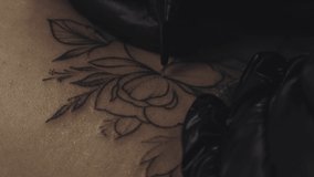 Professional female tattoo artist makes a tattoo in the studio, close-up. Dark 4k video