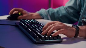 Close-up on Hands man Gamer Playing in Video Game Using Keyboard. Male Hacker Breaks into System.Young hipster man playing online computer video game, colorful lighting broadcast streaming live home