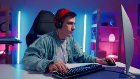 Young hipster man playing online computer video game, colorful lighting broadcast streaming live home. Ecstatic celebration winning match. Gamer lifestyle, E-Sport online gaming technology concept