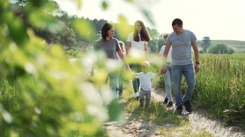 Family trip. Children learn to walk. Happy family. Picnic in forest garden on grass. Mother love for children.Hiking people in forest garden.Family walk in nature.Parents with children playing in park