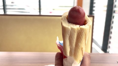 hot dog. American sausage in a fast food cafe at a gas station. lunch snack out of the house concept. hot dog with sausage blurred cafe in the background. store meat hot dog lifestyle food