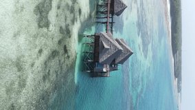 Vertical video house on stilts in the ocean on the coast of Zanzibar, Tanzania, aerial view