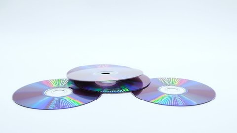 Pile of cd rom disk falling on white background slowmotion, optical data storage technology