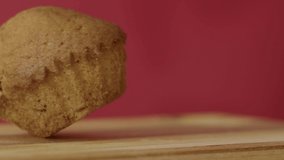 Fresh cupcake falls on a wooden board on a red background, delicious and sweet baked. Slow motion, 4K.