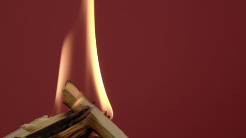 The wooden fire is orange, and the smoke of the fire from the mustard tree is on a red background. Close-up of a flame with white smoke. Slow motion, 4K.