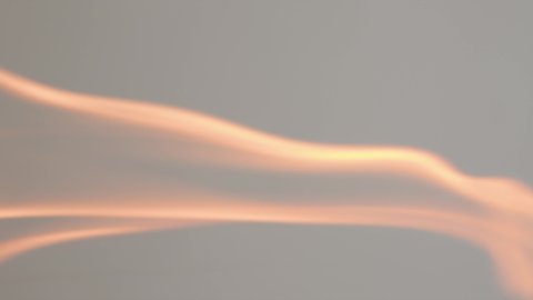 The wooden fire is orange, and the smoke of the fire from the mustard tree is on a grey background. Close-up of a flame with white smoke. Slow motion, 4K.