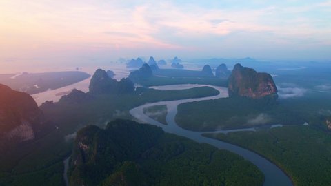 The drone flying over a river with a large mangrove forest. Mist over the mangrove forest, beautiful sunrise. Phang Nga Bay, Phang Nga Province, Thailand. 4K
