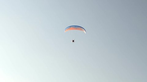 Beautiful view of flying man on hang glider against background cloudless sky. Greece.