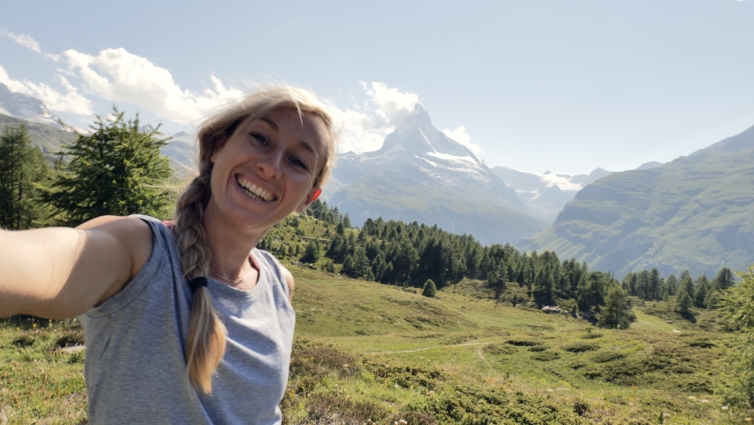Woman hiking in summer in the Swiss Alps takes a selfie with the Matterhorn mountain in Zermatt, Switzerland 