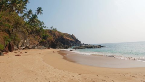 4K Wide angle shot of Kakolem beach besides the mountain at Goa in India. Unexplored hidden tropical beach in India. Beach besides the mountain and palm tree forest. Natural tropical Background. 