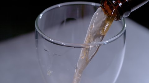 SUPER SLOW MOTION, CLOSE UP: Detailed view of pouring cold beer from bottle into the beer glass. Splashing liquid movement while pouring beverage from bottle to glass. Refreshment for summer days.
