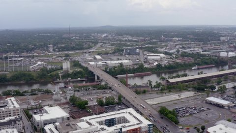 Nashville, Tennessee, USA - May 6 2022: Slow dolly and pan move from left to right from Jefferson Street bridge to Nashville skyline. Aerial, drone shot angle. Cloudy day. Cumberland River.