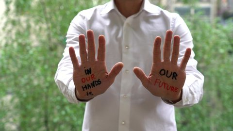 MAN WITH WRITING ON HANDS IN OUR HAND IS OUR FUTURE. SELF-ESTEEM AND CONFIDENCE IN THE FUTURE IN A TIME OF ECONOMIC CRISIS, WAR AND CLIMATE CHANGE. SET A GOAL AND ACHIEVE IT WITH YOUR SKILLS
