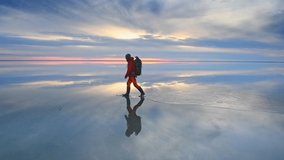 Man traveler with backpack walking on the salt lake at sunset. Blue sky with clouds are reflected in the mirror water surface. Travel and adventure concept
 - Powered by Shutterstock - Get 15% off with code: PIKWIZARD15
