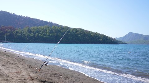 Row of three fishing rods on sea beach in scenic windy landscape. 4k stock video footage of beautiful turkish landscape, Marmaris, Turkey country. Fishing concept