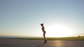 Beautiful young girl dancing on roller skates with cinematic sunset in the background. Stylish woman enjoys sunny weather at cycle track. High quality 4k footage