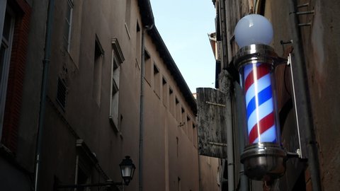 A traditional spinning barbershop pole on a city streetcorner at dusk - isolated
