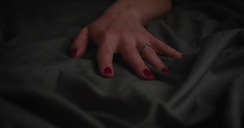 Hands of woman holding on blanket while lying on the bed orgasm sexuality on bed at home. Unknown sexy model girl dreaming about sex pleasure
