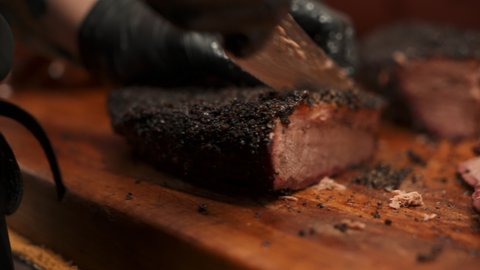 Pitmaster carves juicy lean Texas barbecue smoked brisket, carefeully slicing tender beef brisket for bbq plates, slow motion close up 4K