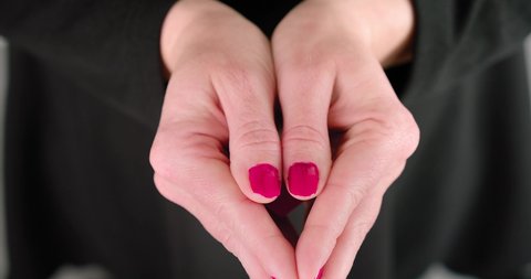 Hand of woman uncovers and offers pink heart, close up view