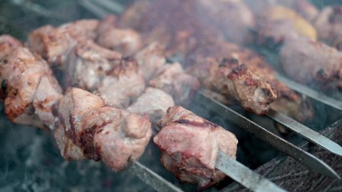 Shish kebab is grilled on skewers on the open barbecue at the food court. Street food at the festival. Hot beef shashlik prepares on coals. cooking grilled appetizing meat on BBQ.