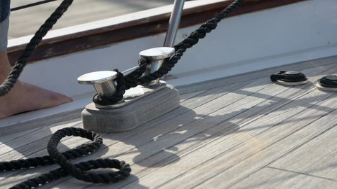 lateral handheld shot of male hands tying a cleat hitch on the boat in sunshine, Alicante, Spain.