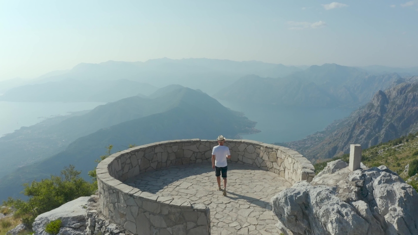 A tourist in a viewpoint looks at the beautiful landscape of the Bay of Kotor in Montenegro Royalty-Free Stock Footage #1090004147