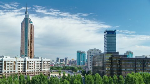 New business district aerial timelapse with traffic on road from mosque roof in the capital of Kazakhstan in Astana. Green trees in park. Nur-Sultan city skyline panorama