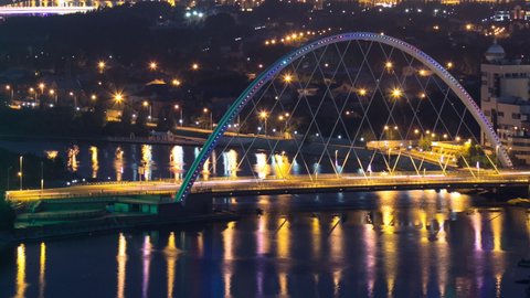 River and illuminated bridge reflected on water aerial timelapse from rooftop at night in Astana. Nur-Sultan city, Kazakhstan capital