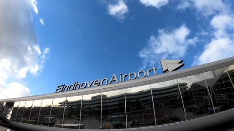 Eindhoven, Netherlands, January 30, 2022: PAN SHOT - Eindhoven Airport Terminal. Passengers in front of Modern architecture Eindhoven airport.