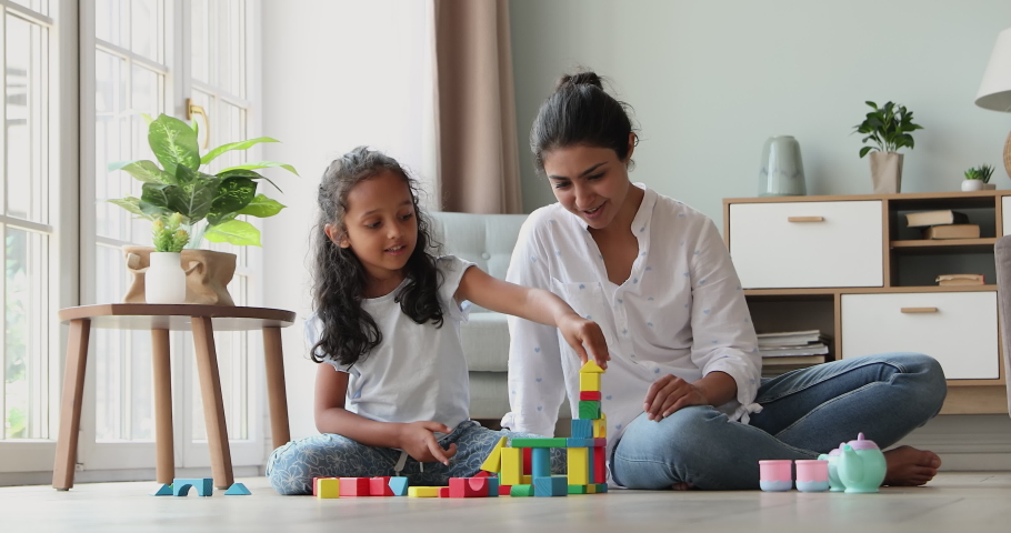 Smart little Indian girl play on warm floor with mom construct from brick set receive praise from parent. Happy preschooler child give high five to mum celebrate success in building fantasy toy castle Royalty-Free Stock Footage #1090009065