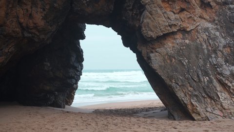 Ocean wild beach stormy weather. Gate on the Praia da Adraga beach, a North Atlantic beach in Portugal, Sintra Cascais, Portugal Handheld effect. 